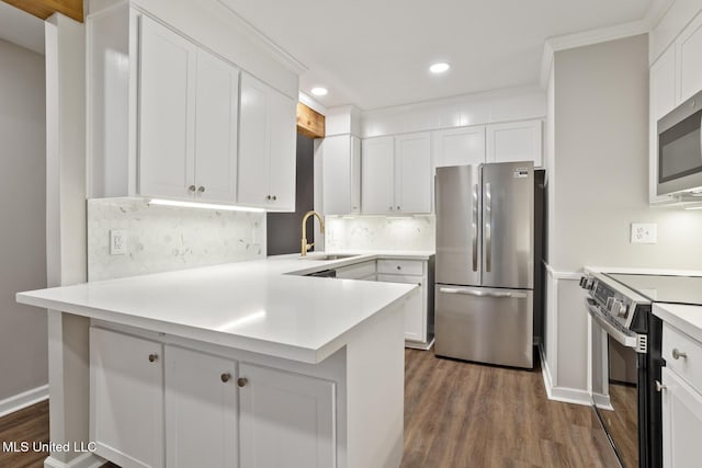 kitchen with dark hardwood / wood-style floors, white cabinetry, sink, kitchen peninsula, and stainless steel appliances