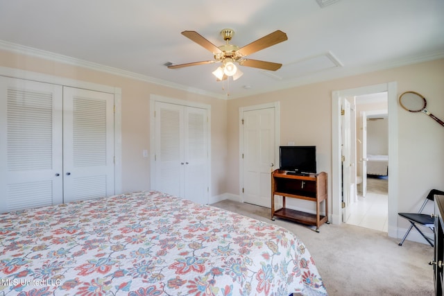 bedroom featuring ceiling fan, visible vents, crown molding, two closets, and light colored carpet