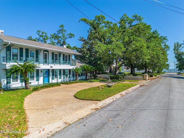 view of front of property with a balcony and curved driveway