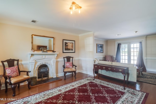 sitting room featuring crown molding, visible vents, wood finished floors, and a fireplace with raised hearth