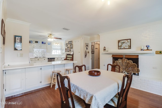 dining room featuring brick wall, crown molding, visible vents, and dark wood finished floors