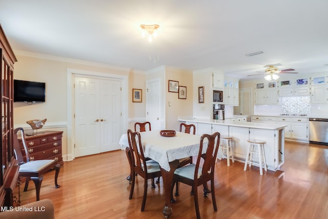 dining space featuring light wood-type flooring, visible vents, wainscoting, ceiling fan, and ornamental molding
