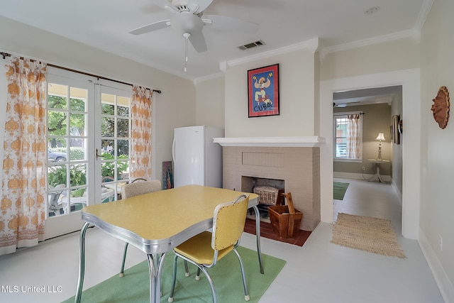 dining space with ornamental molding, ceiling fan, and a fireplace