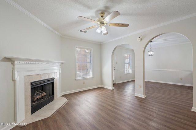 unfurnished living room with a tiled fireplace, ornamental molding, hardwood / wood-style floors, and a textured ceiling