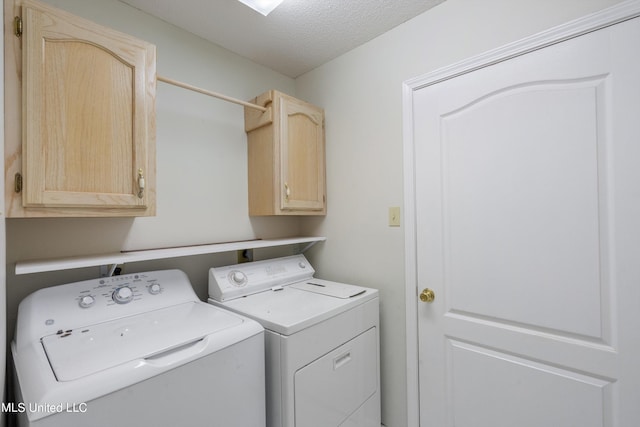 washroom featuring cabinets, a textured ceiling, and washing machine and clothes dryer