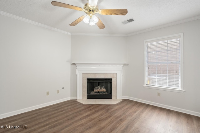 unfurnished living room featuring wood finished floors, crown molding, a tiled fireplace, baseboards, and ceiling fan