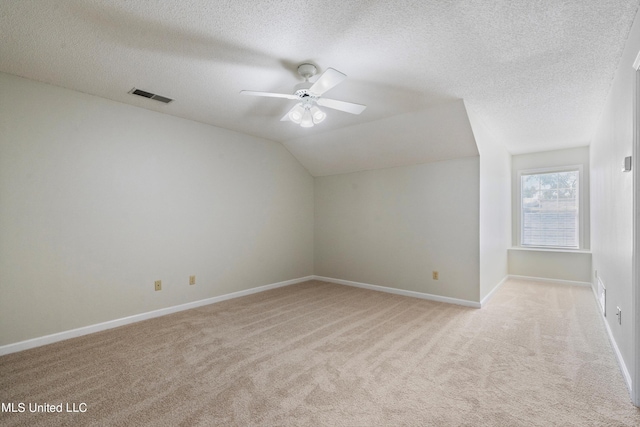 additional living space featuring light colored carpet, ceiling fan, a textured ceiling, baseboards, and lofted ceiling