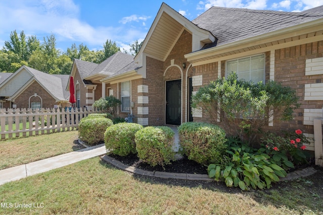 doorway to property featuring brick siding and a shingled roof