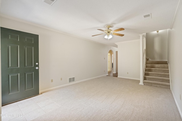 spare room with arched walkways, a ceiling fan, crown molding, stairs, and light colored carpet