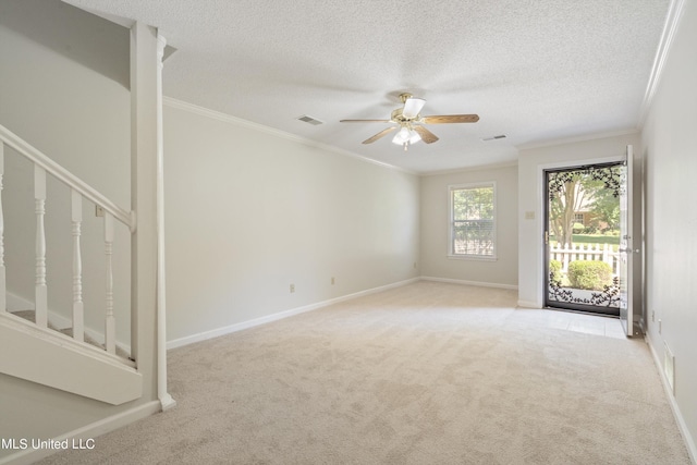 spare room featuring carpet flooring, crown molding, ceiling fan, baseboards, and stairway