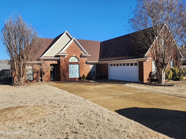 view of front of house featuring an attached garage, roof with shingles, concrete driveway, and brick siding