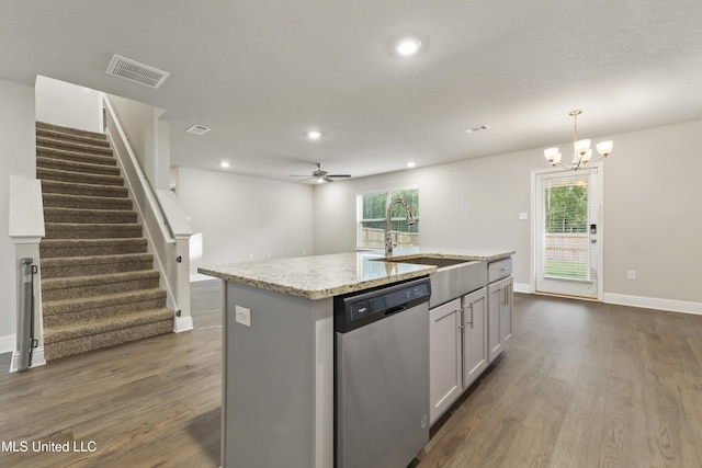 kitchen with stainless steel dishwasher, ceiling fan with notable chandelier, a kitchen island with sink, sink, and pendant lighting