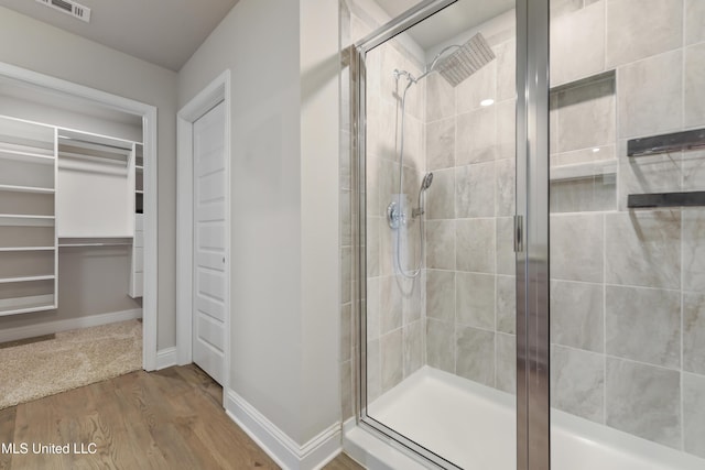 bathroom with a shower with door and hardwood / wood-style flooring