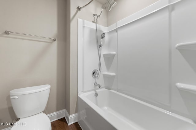 bathroom featuring hardwood / wood-style floors, washtub / shower combination, and toilet