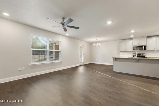 unfurnished living room with dark hardwood / wood-style flooring and ceiling fan with notable chandelier