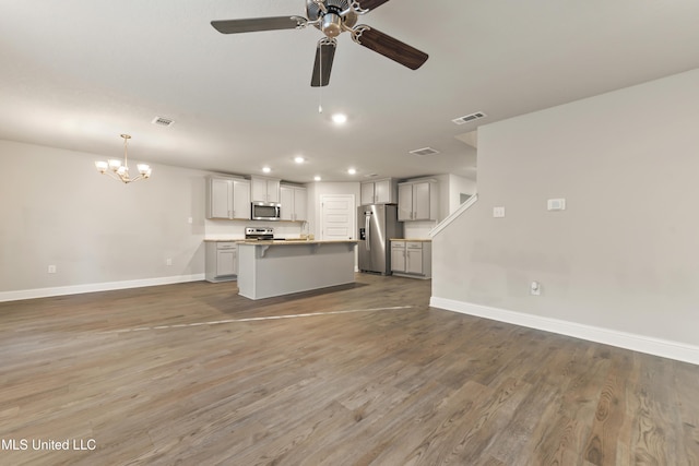 unfurnished living room with wood-type flooring and ceiling fan with notable chandelier