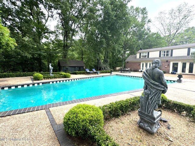 59 Dunbar Rd, Natchez, MS 39120 - outdoor pool featuring french doors, a patio area, view of wooded area, and an outbuilding