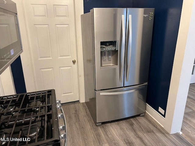 kitchen featuring baseboards, appliances with stainless steel finishes, and wood finished floors