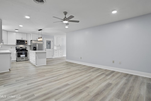 kitchen featuring appliances with stainless steel finishes, pendant lighting, white cabinetry, a center island, and light hardwood / wood-style floors