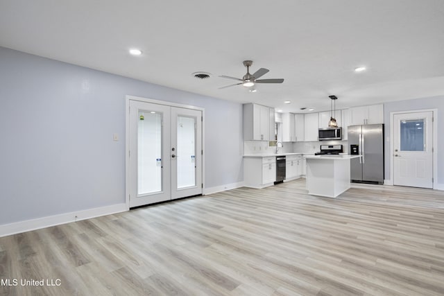 kitchen with white cabinets, hanging light fixtures, a center island, stainless steel appliances, and french doors