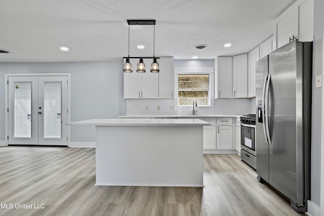 kitchen featuring light hardwood / wood-style flooring, white cabinetry, hanging light fixtures, stainless steel appliances, and a kitchen island