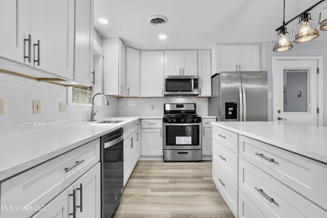 kitchen with stainless steel appliances, white cabinetry, sink, and tasteful backsplash