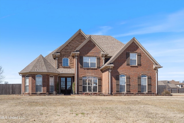 view of front of property with brick siding, roof with shingles, and fence