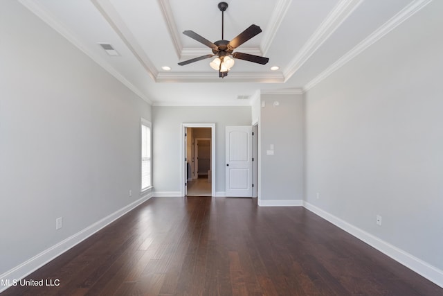 spare room featuring dark wood-style floors, a tray ceiling, visible vents, and baseboards