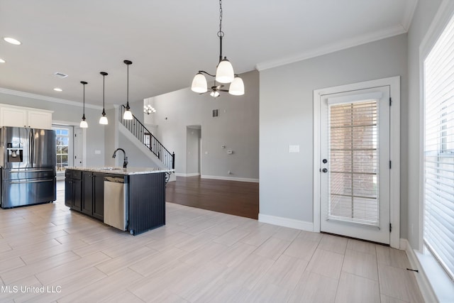 kitchen featuring decorative light fixtures, crown molding, appliances with stainless steel finishes, a sink, and baseboards