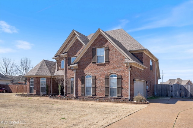 view of front of property featuring brick siding, an attached garage, a gate, fence, and a front yard