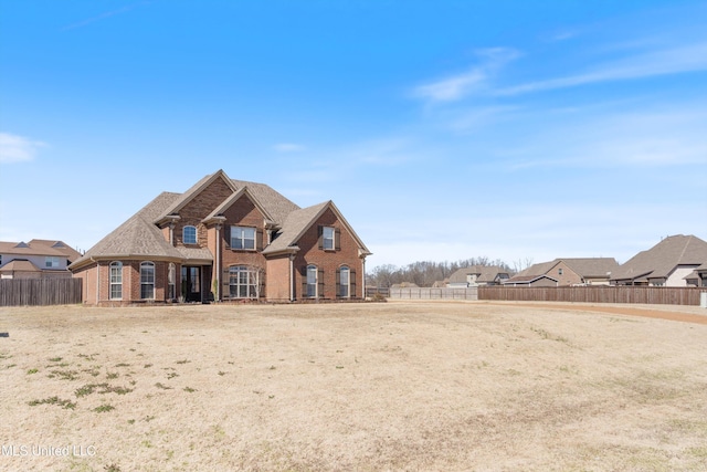 rear view of property with brick siding, a shingled roof, and fence