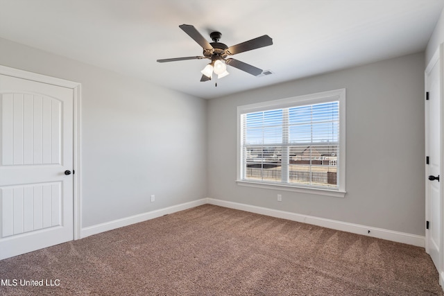 carpeted empty room with visible vents, baseboards, and ceiling fan