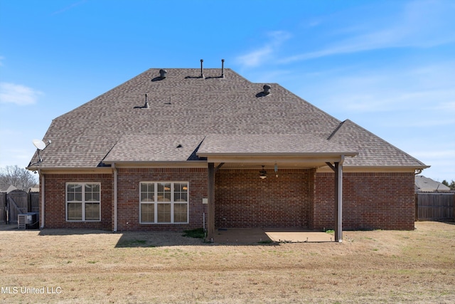 rear view of property featuring a shingled roof, a lawn, and a patio area