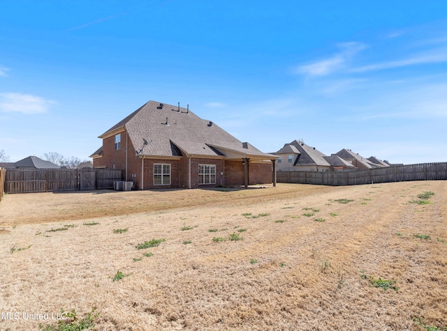 back of house with brick siding, a fenced backyard, and central air condition unit