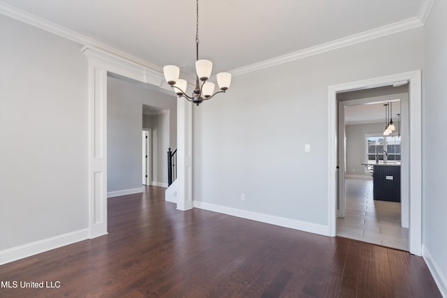 empty room featuring ornamental molding, dark wood-style flooring, and an inviting chandelier