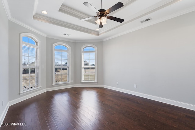 unfurnished room featuring dark wood-type flooring, a wealth of natural light, a raised ceiling, and visible vents