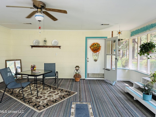 dining area with ceiling fan, plenty of natural light, and dark colored carpet