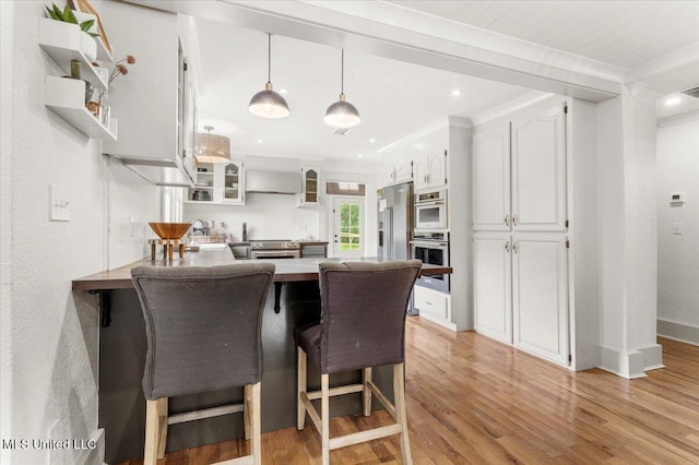 7101 Wayne Ln, Biloxi, MS 39532 - kitchen with a peninsula, light wood-type flooring, glass insert cabinets, white cabinets, and ornamental molding