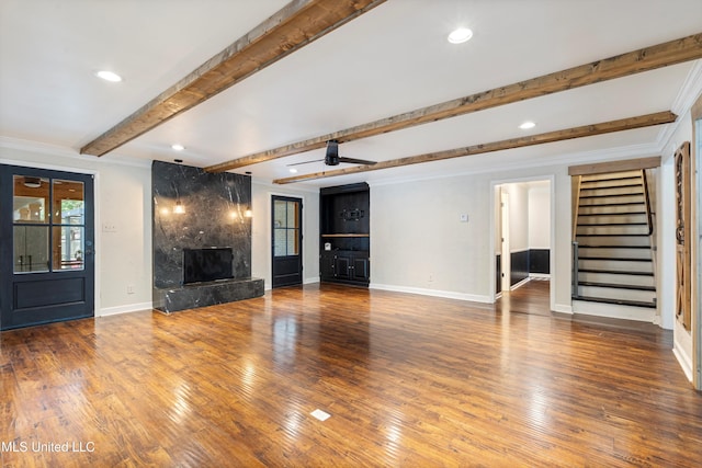 unfurnished living room featuring hardwood / wood-style flooring, ceiling fan, beam ceiling, and a fireplace