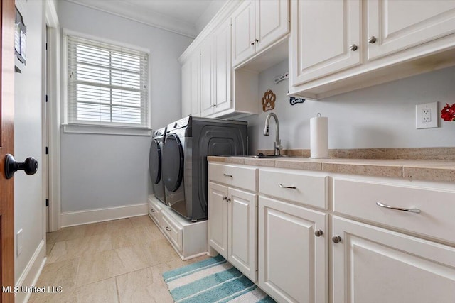 laundry room featuring sink, crown molding, washing machine and dryer, and cabinets