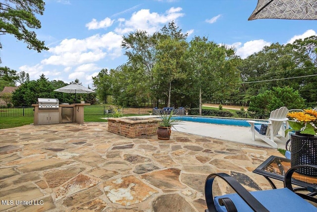 view of patio featuring grilling area, a fenced in pool, and an outdoor kitchen