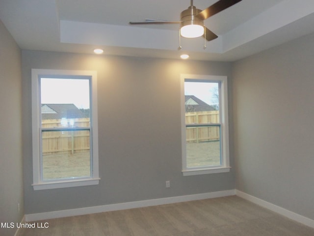 empty room featuring ceiling fan and a tray ceiling