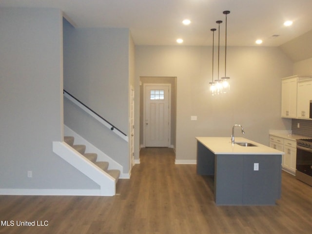 kitchen featuring sink, white cabinetry, decorative light fixtures, stainless steel range, and a kitchen island with sink