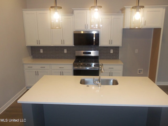 kitchen featuring sink, white cabinetry, hanging light fixtures, appliances with stainless steel finishes, and a kitchen island with sink