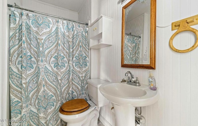 bathroom featuring toilet, wooden walls, and a shower with shower curtain