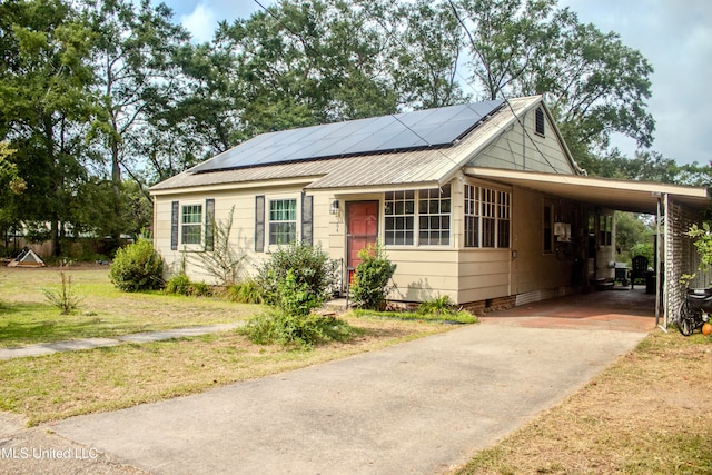 view of front of property featuring solar panels, a front lawn, and a carport