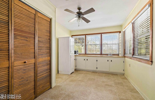 interior space featuring a closet, sink, crown molding, light colored carpet, and ceiling fan