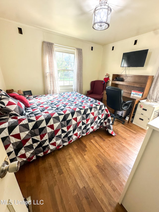 bedroom featuring a chandelier, crown molding, and wood-type flooring