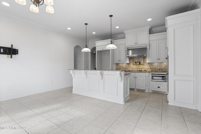 kitchen with a kitchen island, backsplash, hanging light fixtures, ornamental molding, and wall chimney range hood