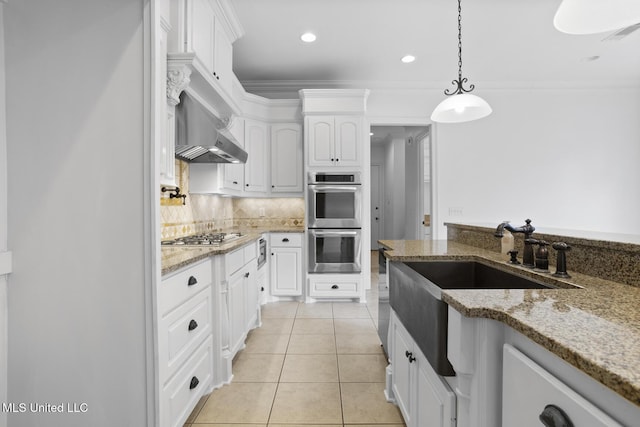 kitchen featuring light tile patterned flooring, light stone counters, appliances with stainless steel finishes, pendant lighting, and white cabinets